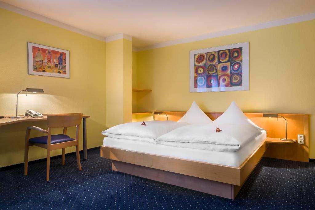 カールスルーエにあるacora Karlsruhe Zentrum Living the Cityのベッドとデスクが備わるホテルルームです。