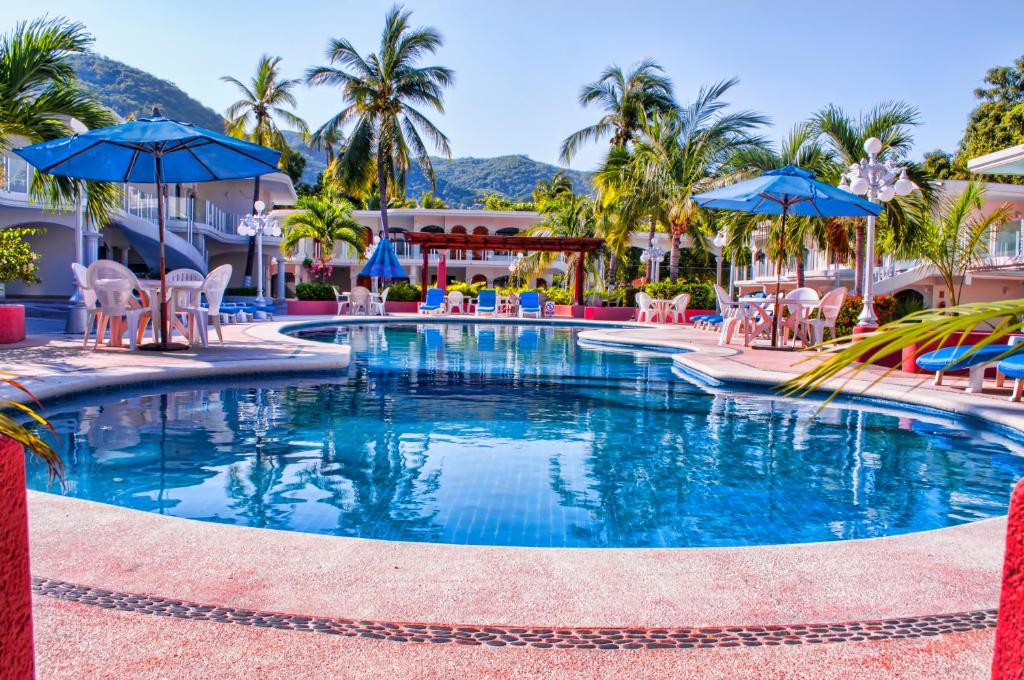 uma piscina num resort com cadeiras e guarda-sóis em Hotel Costa Azul em Acapulco