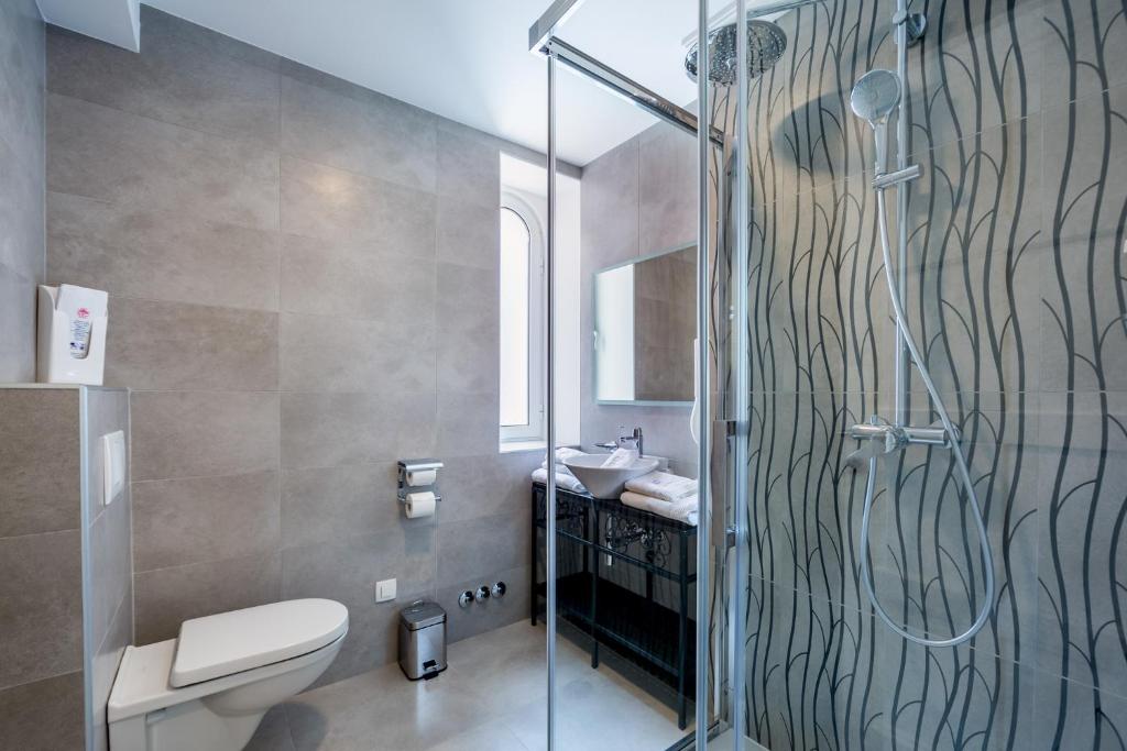 a bathroom with a shower and a toilet and a sink at Hotel Domino in Opatija