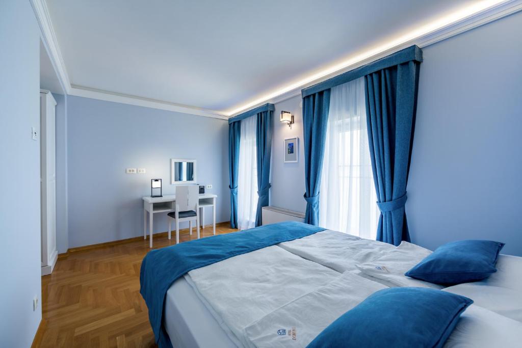 a blue bedroom with a bed and a desk at Hotel Domino in Opatija