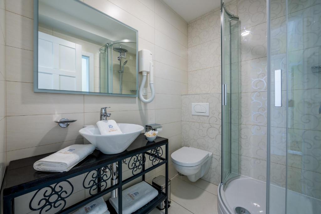 a bathroom with a sink and a shower and a toilet at Hotel Domino in Opatija