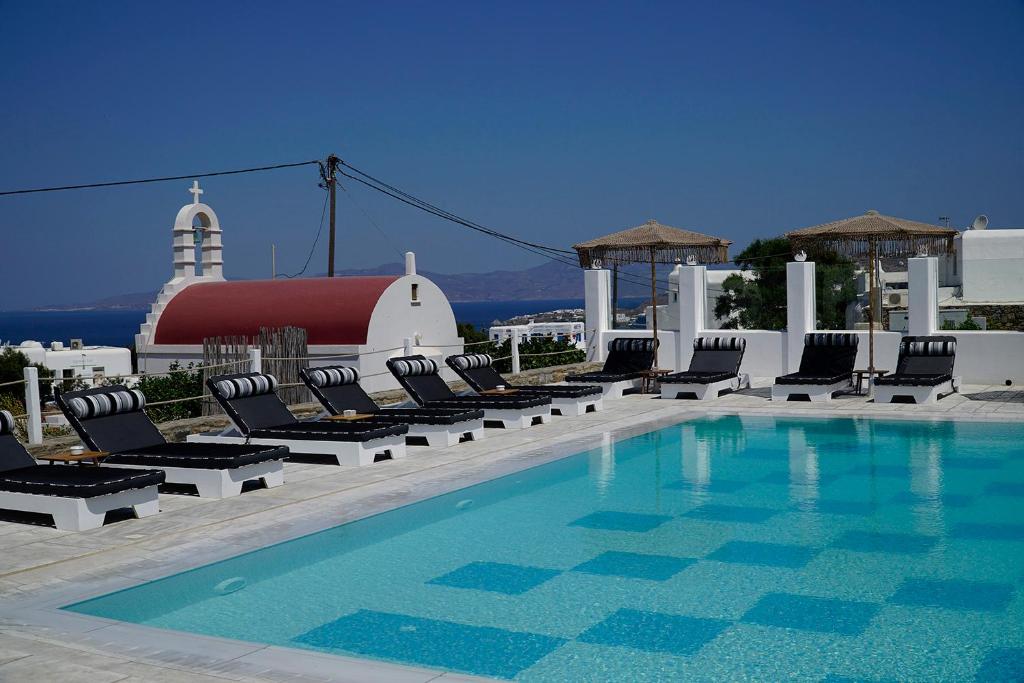 een zwembad met stoelen en een gebouw op de achtergrond bij Margie Mykonos Hotel in Mykonos-stad