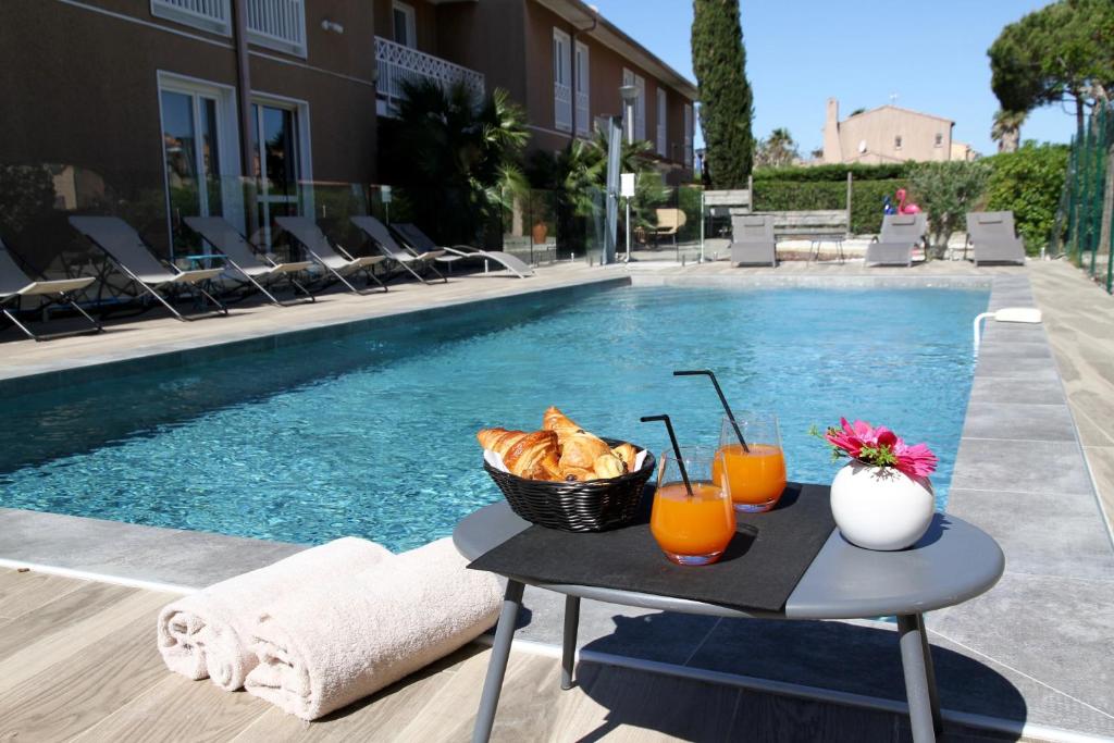 a table with bread and drinks next to a swimming pool at Best Western Plus Hyères Côte D'Azur in Hyères