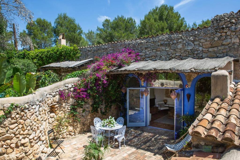 ein Steinhaus mit einem Tisch und Blumen in der Unterkunft Casa Azul at Masia Nur Sitges, Adults only in Canyelles