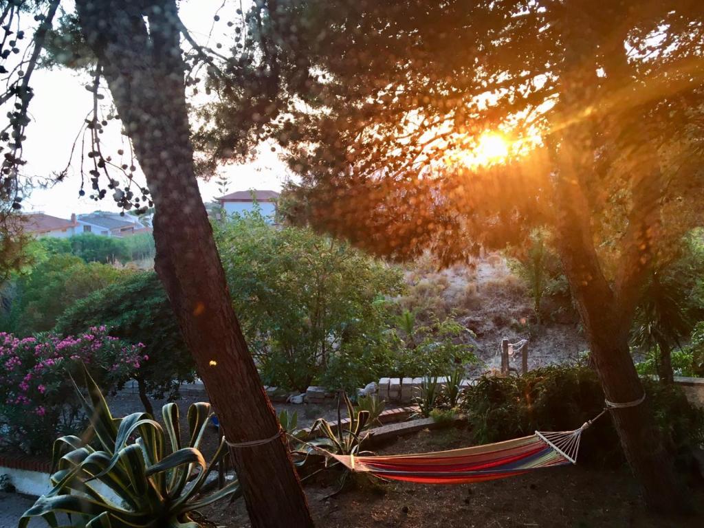 a hammock in a garden with the sun setting at Holiday House Torre Di Manfria in Gela