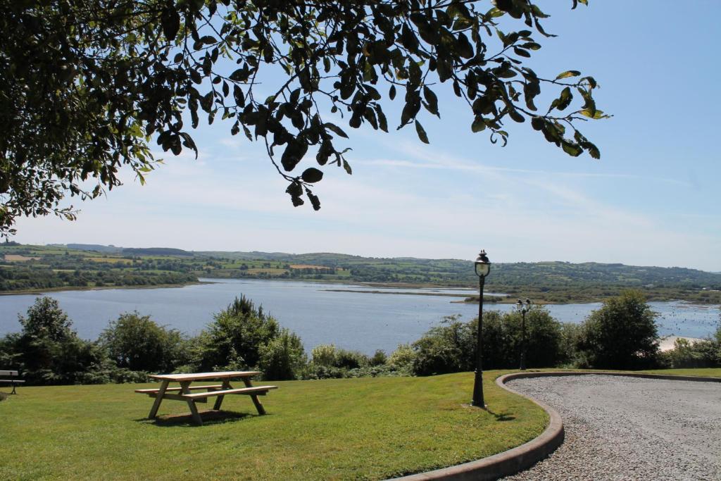 a picnic table in a park with a view of a lake at The Loft, Apple Lodge & Blossom Lodge in Macroom