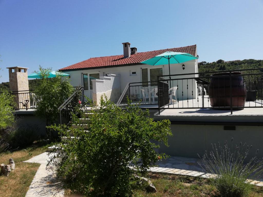 a house with a balcony with an umbrella at Apartmani Goga in Skradin