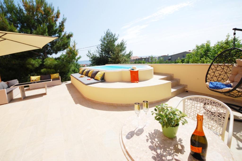 a patio with a couch and a table with a bottle of wine at Apartmant with Pool 8 in Kaštela