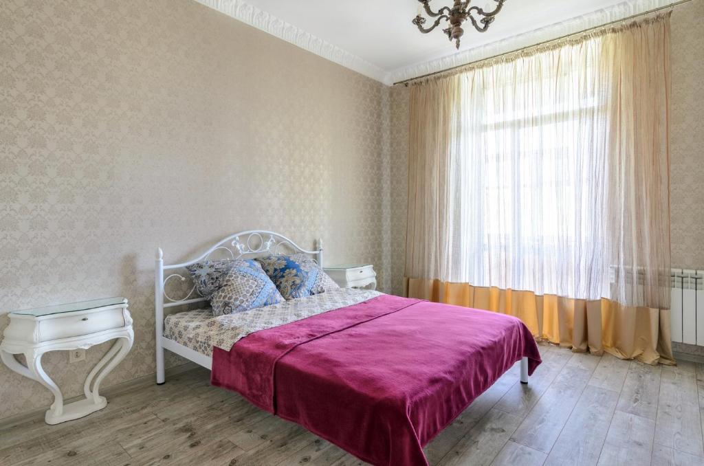 een slaapkamer met een bed met een paarse deken en een raam bij Rest Home in Sumy