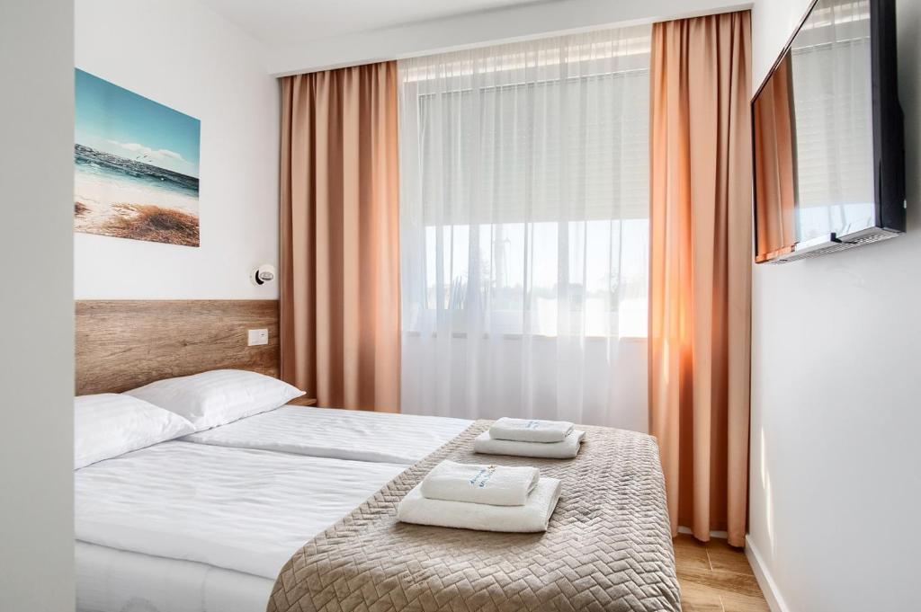 ein Schlafzimmer mit einem Bett mit zwei Handtüchern darauf in der Unterkunft Apartament przy Plaży / Klifowa in Rewal