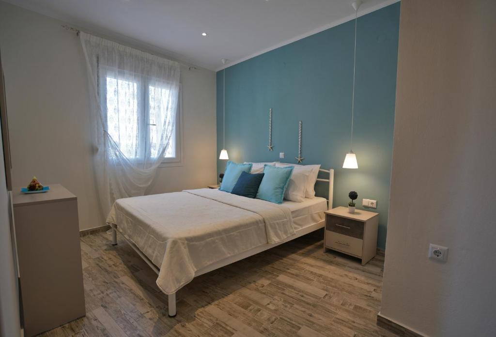 a bedroom with a bed with blue walls and a window at Evel House in Skala Kallirachis