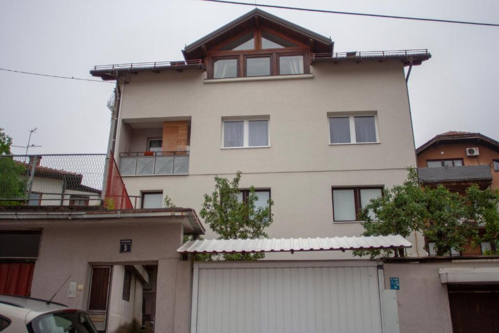 een groot wit huis met een garage bij Guest House Fena in Sarajevo