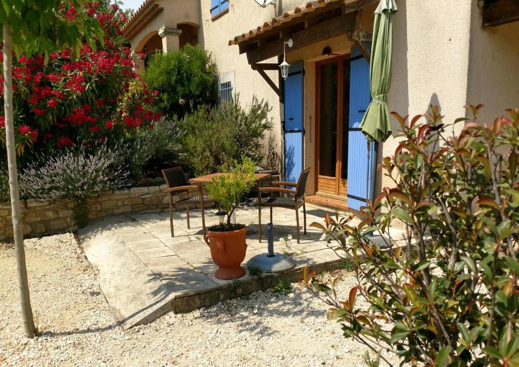 a patio with two chairs and a table and an umbrella at Villa Sénégas in La Roque-sur-Cèze