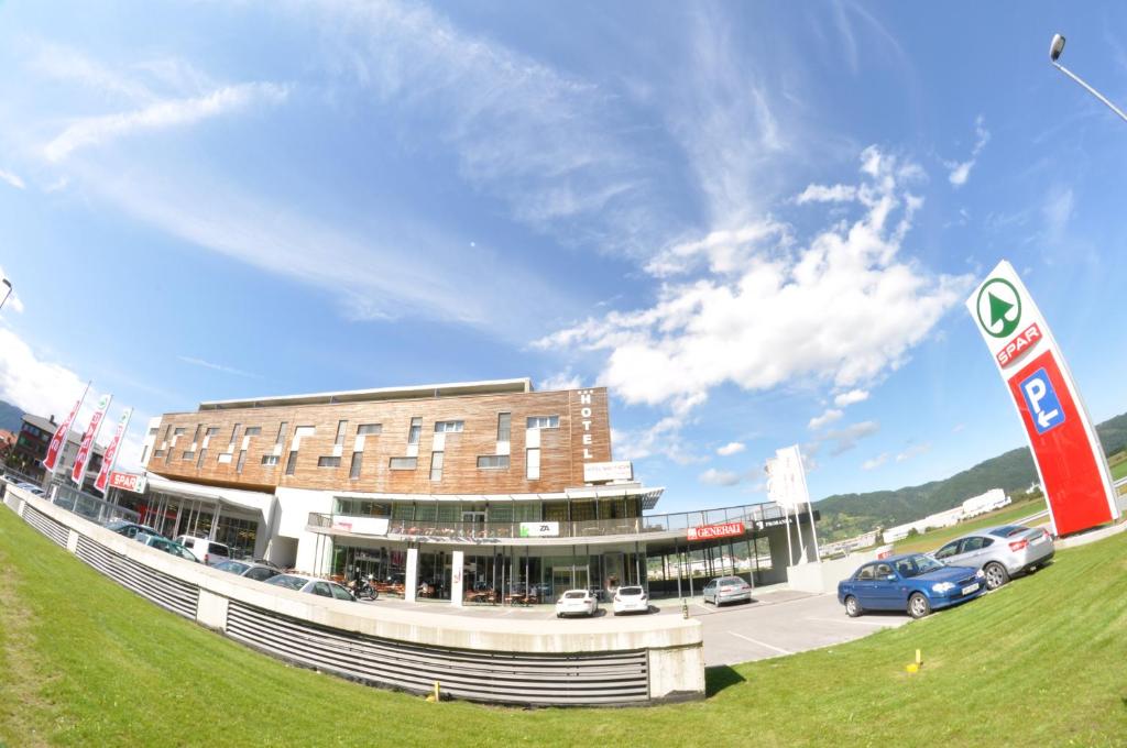 a building with cars parked in a parking lot at Hotel Veter in Ruše