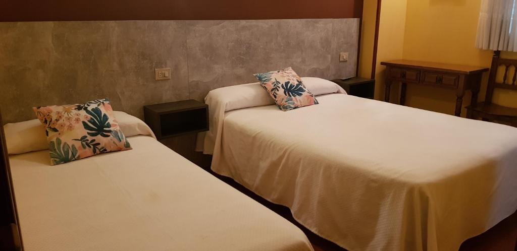 a hotel room with two beds with pillows on them at Hostal Fisterra in Lugo