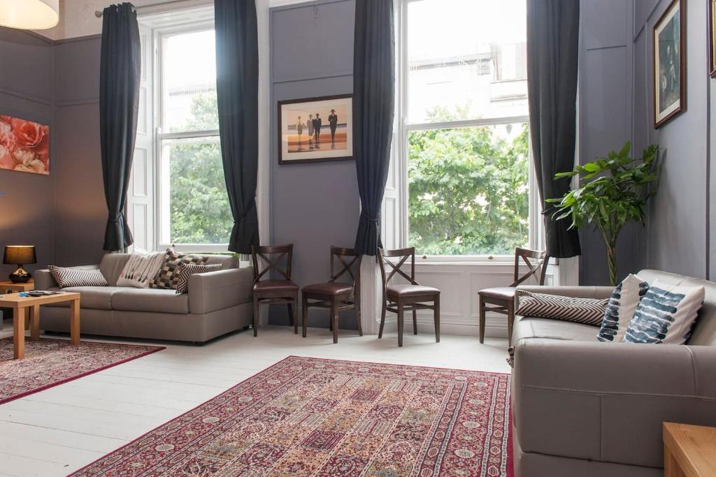 een woonkamer met een bank, stoelen en ramen bij Georgian Grand Apartment in Dublin