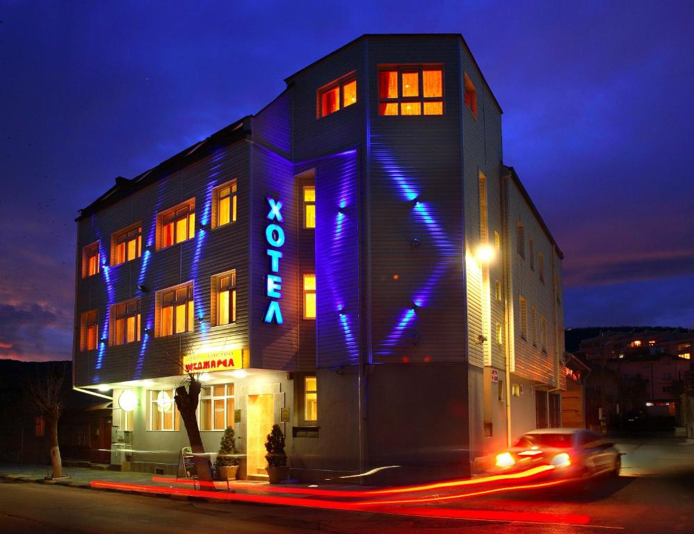 a building with a blue sign on it at night at Hotel Mehdjarel in Shumen
