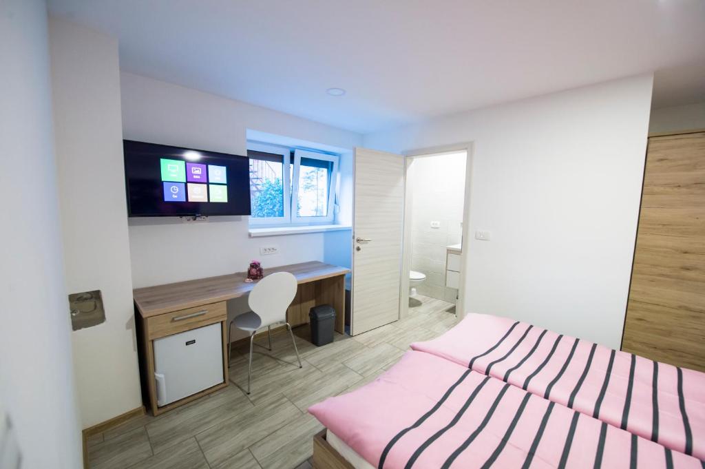 1 dormitorio con cama rosa y escritorio en Guesthouse Urša, en Preddvor