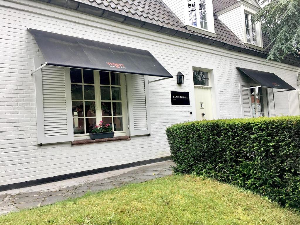 a white house with a black awning and a window at Maison Blanche in Wielsbeke