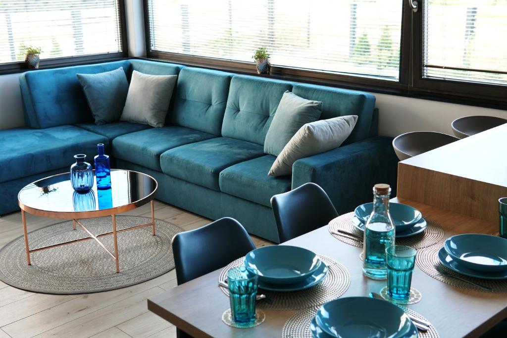 a living room with a blue couch and tables at Regatowa Przystań in Mechelinki