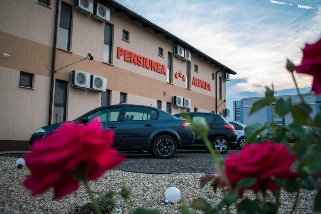 dos autos estacionados en un estacionamiento frente a un edificio en Pensiunea Almada, en Arad