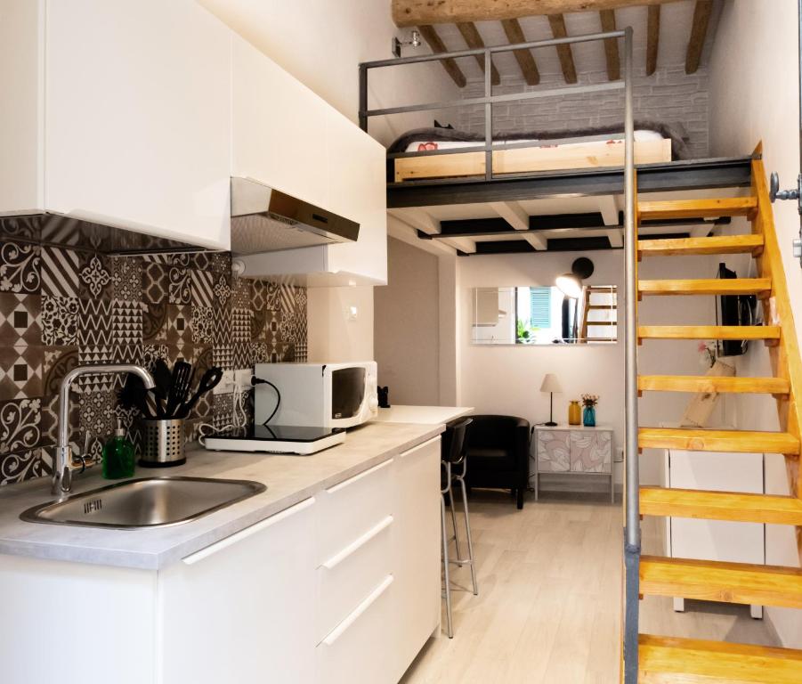 una cucina con lavandino e un letto a soppalco di Il nido - Cozy studio apartment in Santa Croce a Firenze