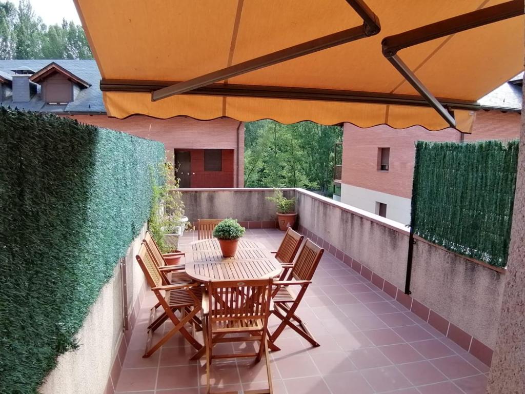 a table and chairs on a balcony with an umbrella at Apartamento Serreria de Boltaña in Boltaña