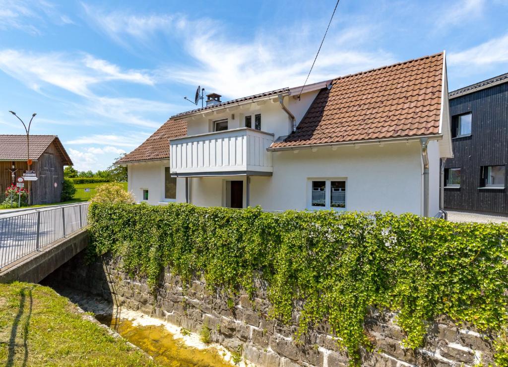 a white house with a brick wall and ivy at Ferienhaus Bachschlössle in Lochau