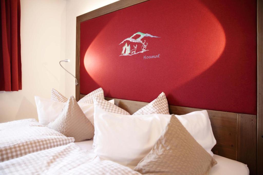 a bed with white pillows and a red wall at Schätzlhof OHG in Ruderting