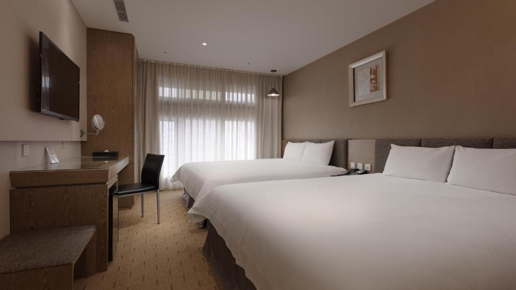 a hotel room with two beds and a television at Fine Hotel in Kaohsiung