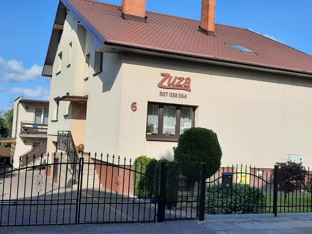 een wit huis met een zwart hek ervoor bij Pokoje gościnne ZUZA in Władysławowo