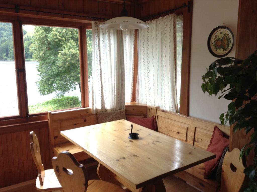 a dining room with a wooden table and a window at Appartements direkt am See in Grundlsee