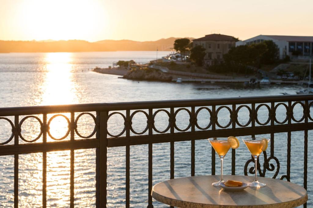 a table with two glasses on a balcony with the ocean at Bounty Apartments in Šibenik