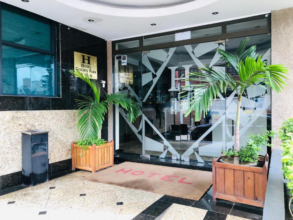 a store front with two palm trees in front of it at Golden Park Hotel in Luanda