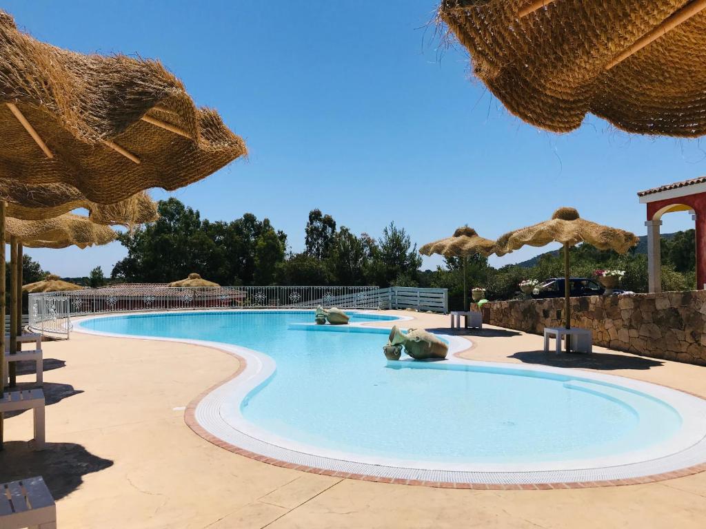 a pool at a resort with umbrellas at Hotel Pedra Niedda in Budoni