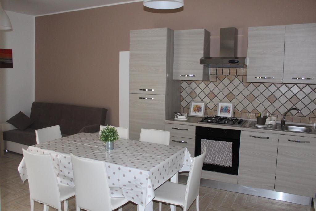 een keuken met een tafel met witte stoelen en een keuken met een fornuis bij AFFITTACAMERE LA TRAVERSA in San Cataldo