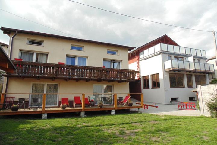 a house with a deck with red chairs in the yard at Magdalenka - pokoje w centrum in Szczyrk