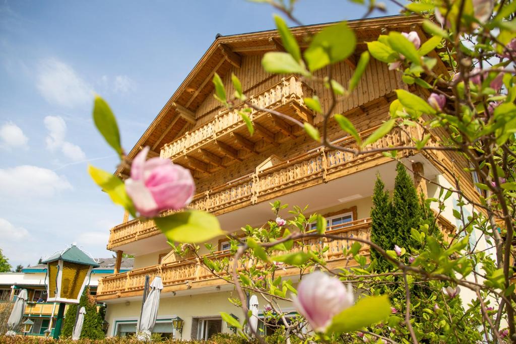 a building with a balcony and pink flowers at Hotel Försterhof lebe pur, genieße den Tag in St. Wolfgang