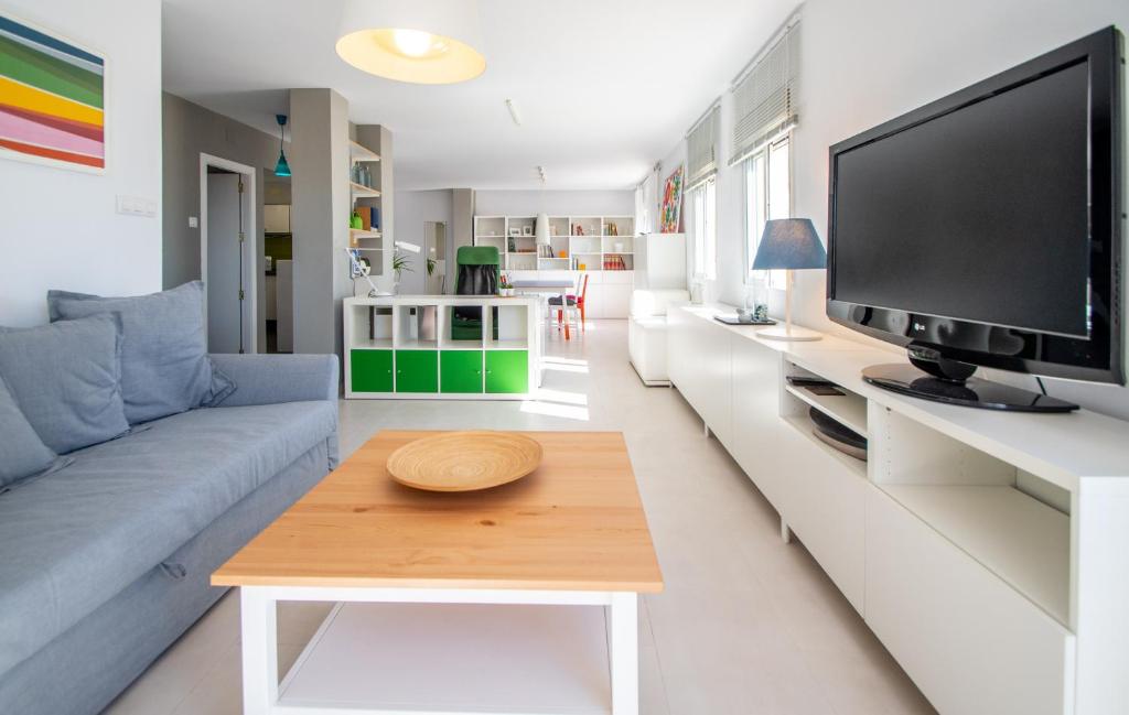 uma sala de estar com um sofá azul e uma televisão em Apartamento El Rayo Verde em Cádiz