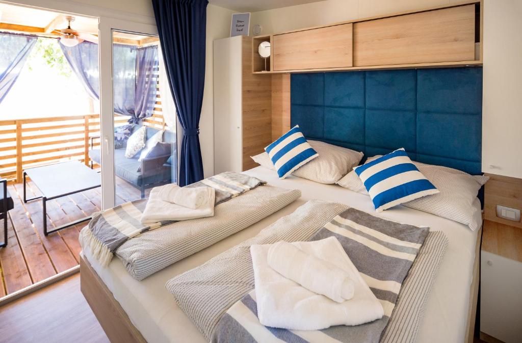 a bedroom with a large bed with blue headboard and pillows at Mobile Home HappyNest in Biograd na Moru