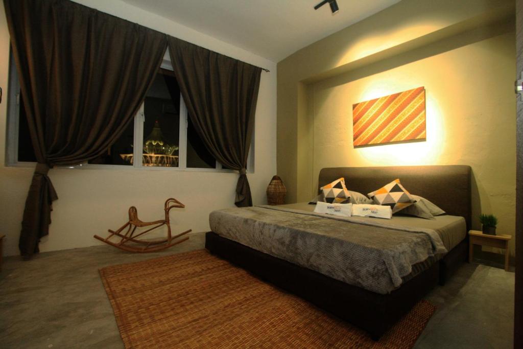 a bedroom with a bed and a window and a chair at Hornbill's Nest Kuching in Kuching