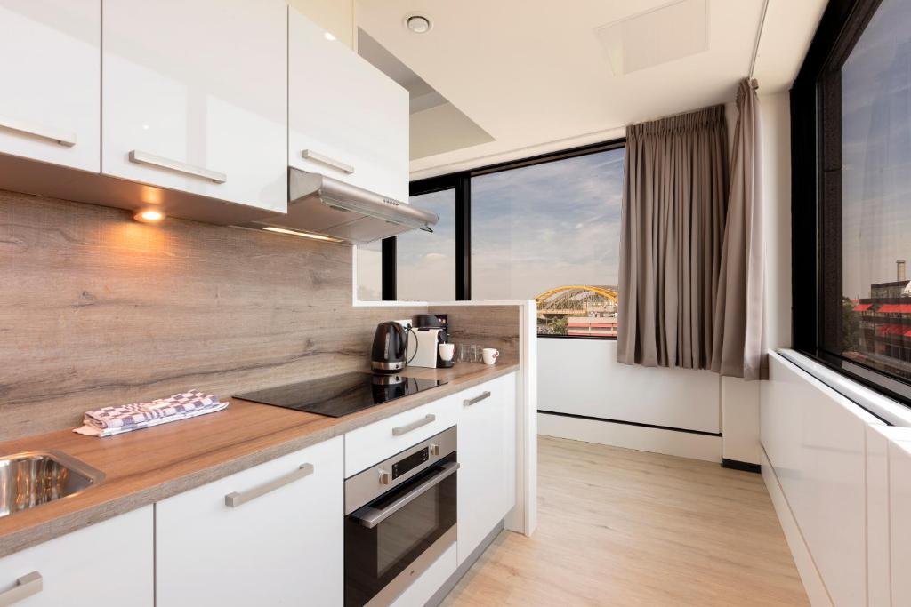 a kitchen with white cabinets and a large window at 2L De Blend in Utrecht