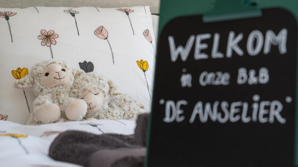 dois bichos de peluche sentados numa cama ao lado de um cartaz em De Anselier em Ansen