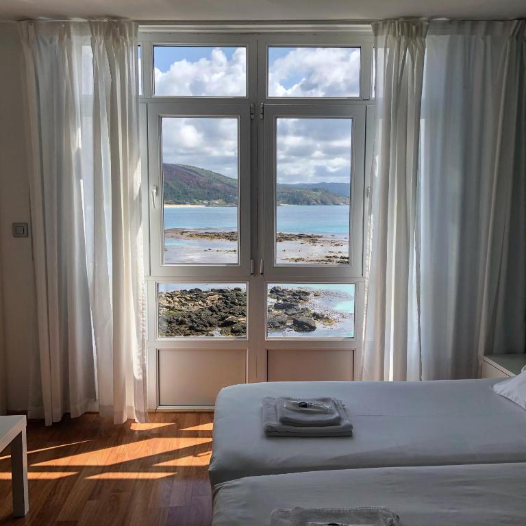 1 dormitorio con ventana grande con vistas al océano en Hotel Mar de Fisterra, en Finisterre