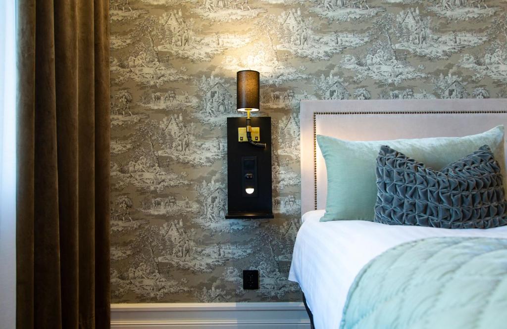 1 dormitorio con 1 cama y 1 lámpara en la pared en Continental du Sud en Ystad