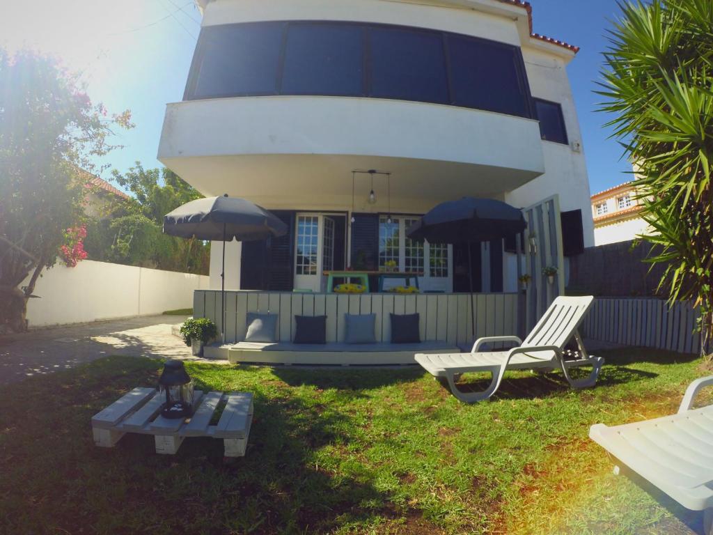 una casa con banco, mesa y sombrilla en Lisbon Waves Surf Lodge en Costa da Caparica