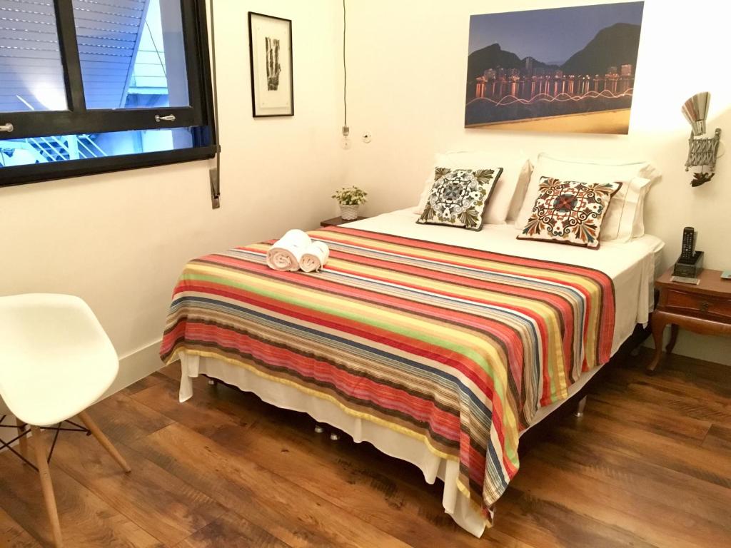 1 dormitorio con 1 cama con manta y silla en Studio2 Rio Beira Mar en Río de Janeiro