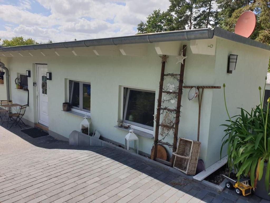 a small white house with a porch at Fe-Wo/Haus Maui bei Berlin m Garten Schulzendorf bei Schönefeld in Schulzendorf