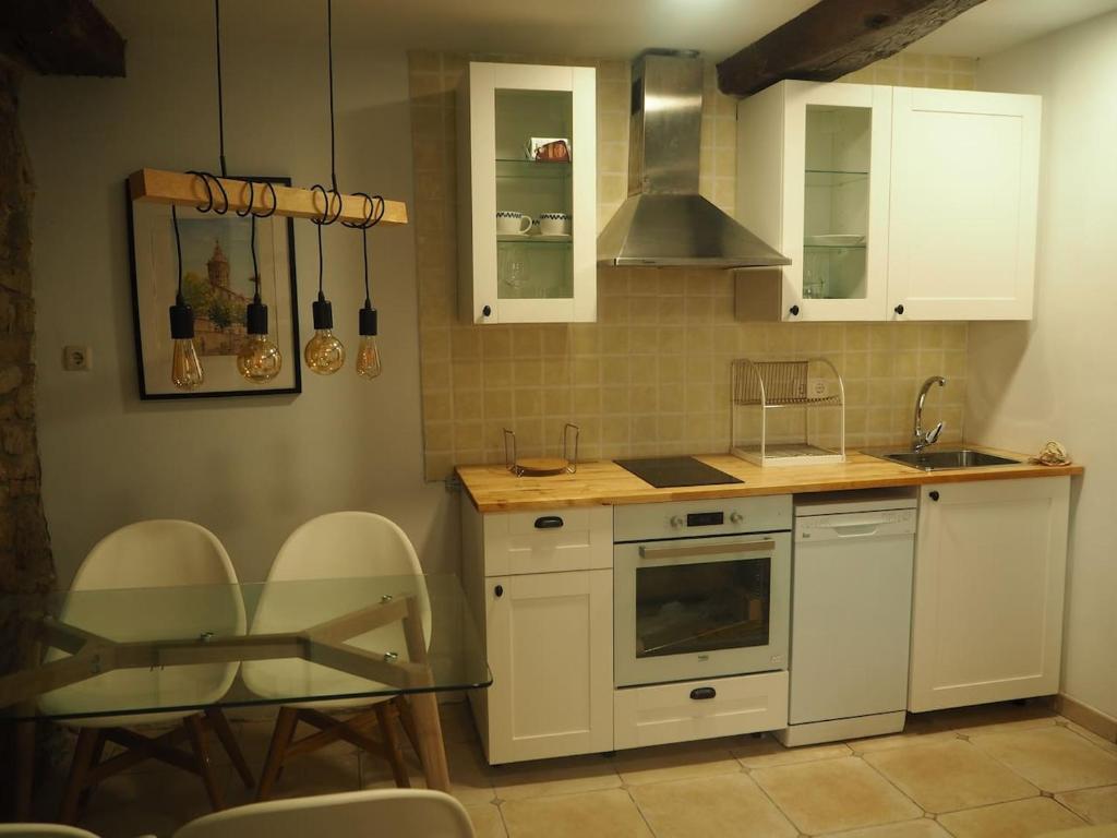 a kitchen with white cabinets and a table and chairs at Piso con encanto en la parte vieja. in Hondarribia