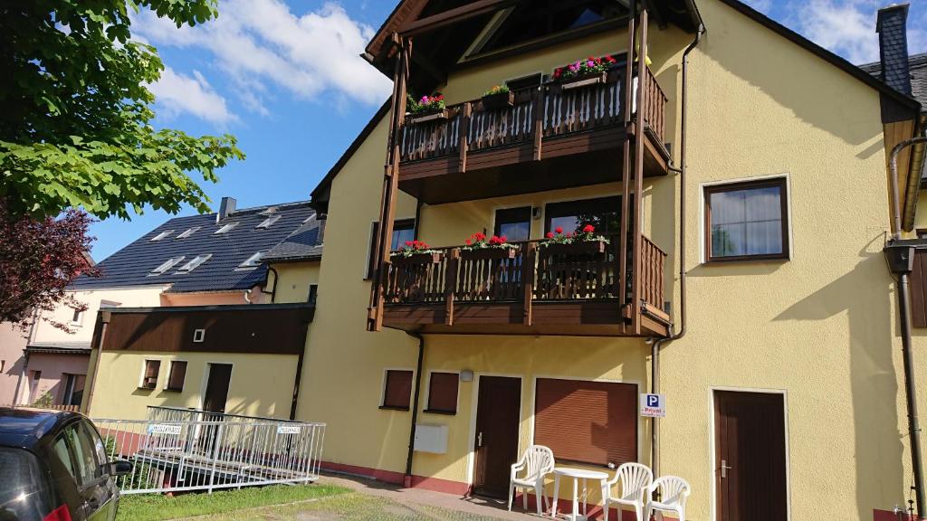 ein Gebäude mit einem Balkon mit Tischen und Stühlen in der Unterkunft Ferienwohnung Korn mit Tiefgarage und Skiraum in Kurort Oberwiesenthal